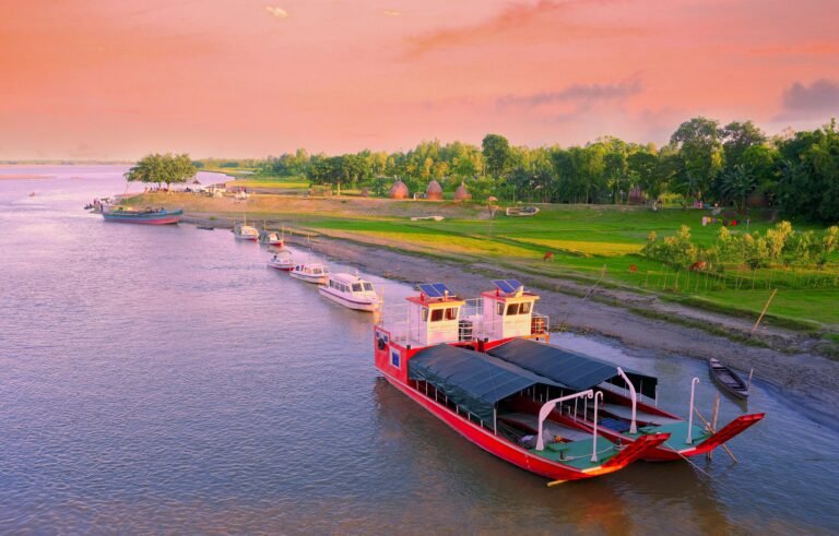 A picturesque aerial view of boats docked along a riverbank during sunset, highlighting tranquil nature.