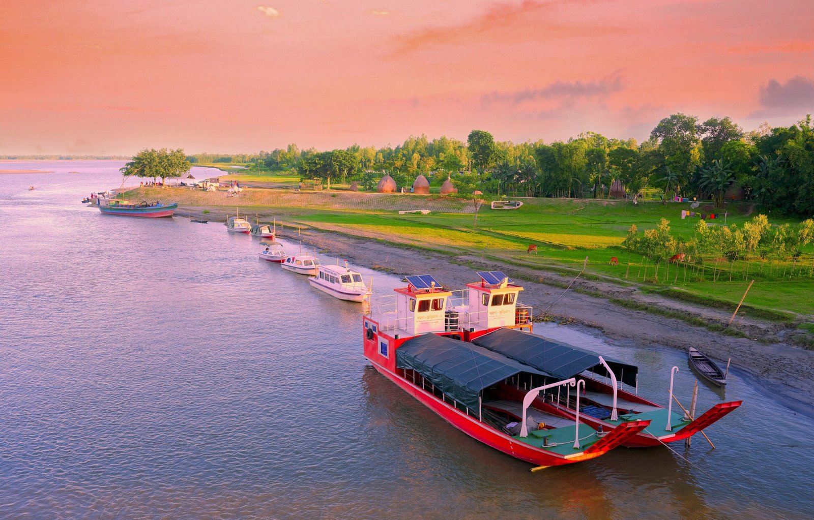 A picturesque aerial view of boats docked along a riverbank during sunset, highlighting tranquil nature.