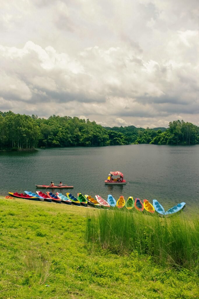 Vibrant canoes on a serene lake in rural Bangladesh, surrounded by lush greenery.