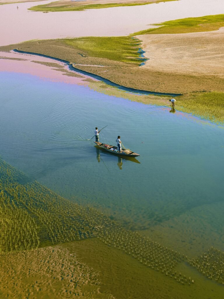 Aerial view of fishermen working in a tranquil river with lush green surroundings.